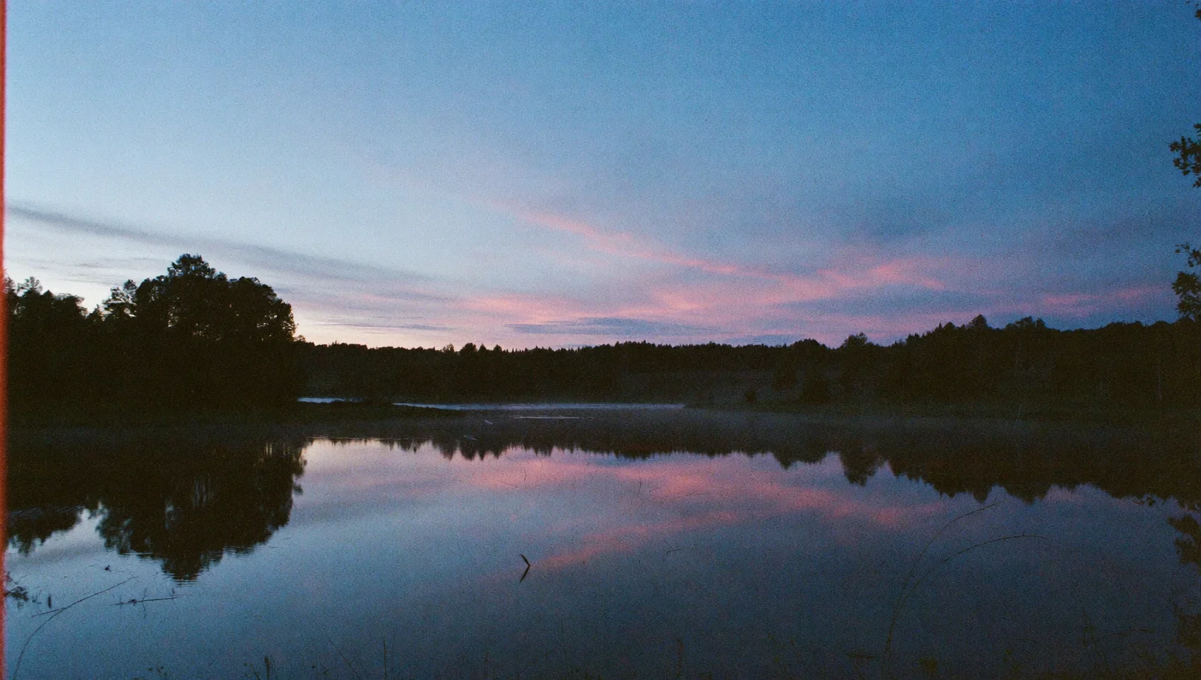 Solnedgång som speglar sig i en stilla sjö